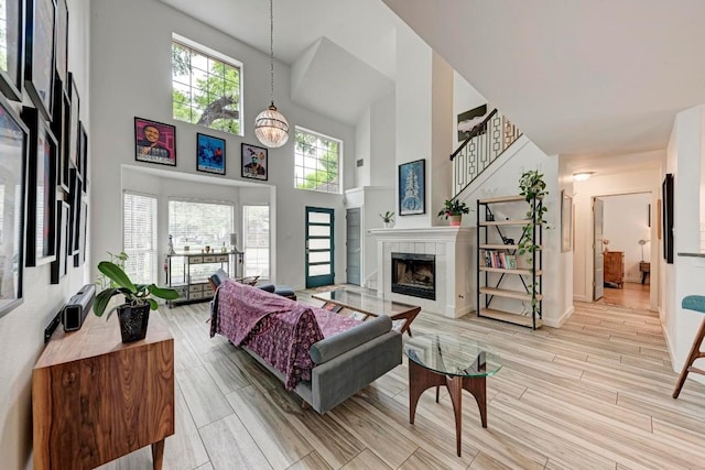12203 Arrowwood Dr, Austin, TX 78727 - living area featuring a high ceiling, a tile fireplace, light wood-style flooring, and stairway