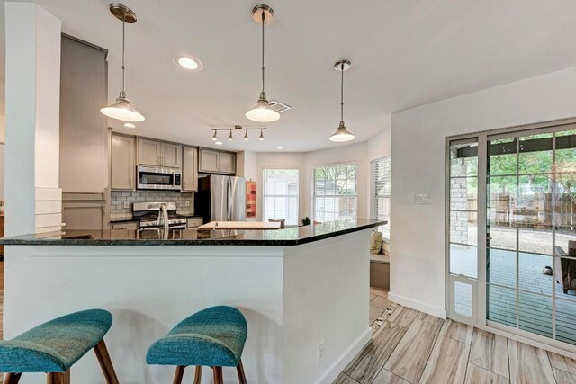 12203 Arrowwood Dr, Austin, TX 78727 - kitchen featuring stainless steel appliances, decorative backsplash, decorative light fixtures, dark stone countertops, and recessed lighting