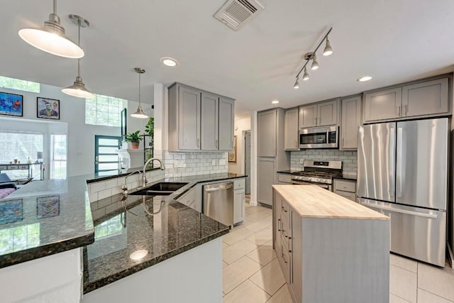 12203 Arrowwood Dr, Austin, TX 78727 - kitchen featuring appliances with stainless steel finishes, gray cabinets, backsplash, dark stone countertops, and recessed lighting