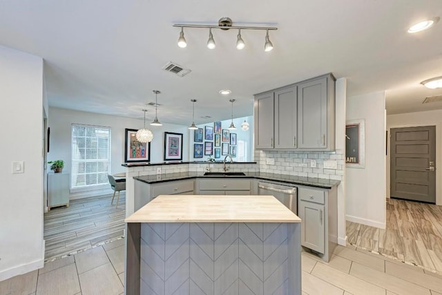 12203 Arrowwood Dr, Austin, TX 78727 - kitchen with a peninsula, gray cabinetry, dishwasher, decorative backsplash, and decorative light fixtures