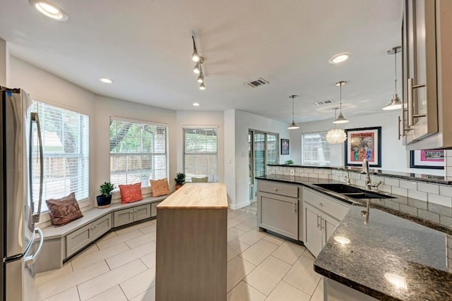 12203 Arrowwood Dr, Austin, TX 78727 - kitchen with freestanding refrigerator, wooden counters, a peninsula, decorative light fixtures, and recessed lighting