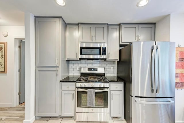12203 Arrowwood Dr, Austin, TX 78727 - kitchen with stainless steel appliances, gray cabinetry, backsplash, dark stone counters, and recessed lighting