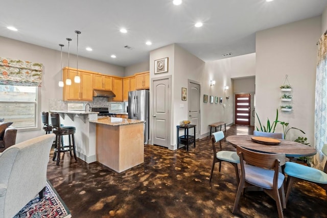 1907 E 20th St, Austin, TX 78722 - kitchen featuring light brown cabinets, a peninsula, under cabinet range hood, finished concrete flooring, and stainless steel appliances