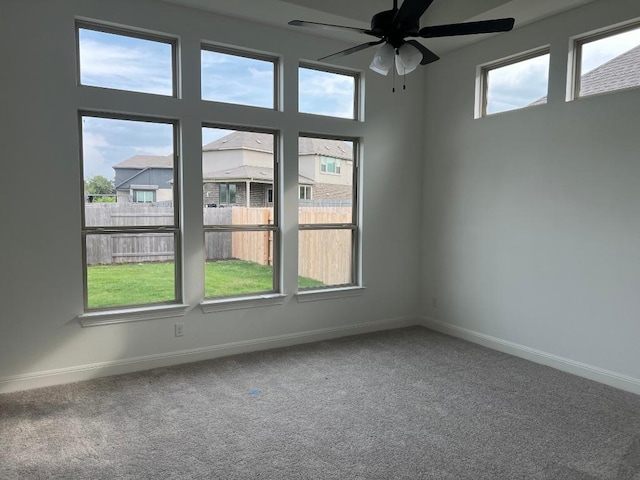 carpeted spare room with a ceiling fan and baseboards