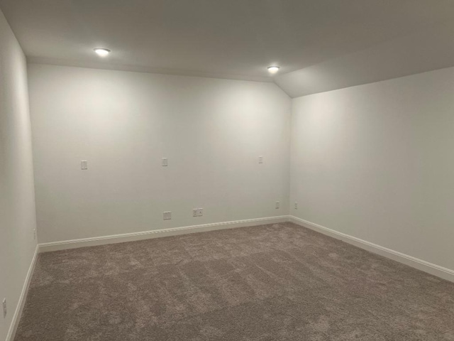 unfurnished room with baseboards, vaulted ceiling, and carpet flooring