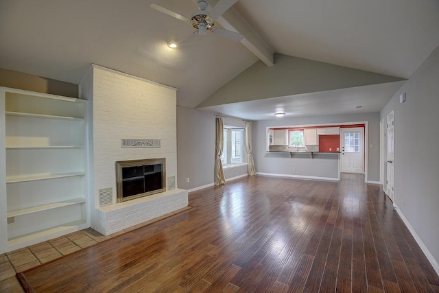 405 E 6th St, Georgetown, TX 78626 - unfurnished living room with a brick fireplace, beamed ceiling, baseboards, ceiling fan, and dark wood finished floors