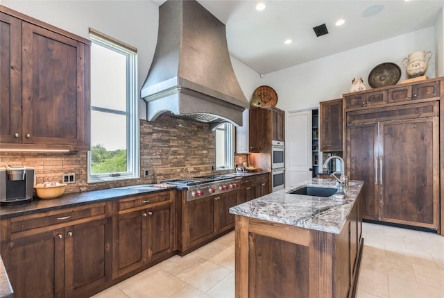 1300 Apache Tears, Horseshoe Bay, TX 78657 - kitchen with stainless steel gas stovetop, premium range hood, paneled built in fridge, light stone counters, and light tile patterned flooring