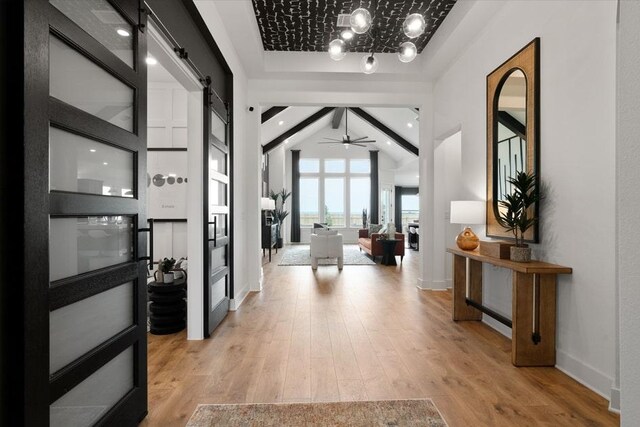 13611 Thomas Wheeler Way, Manor, TX 78653 - entrance foyer featuring a barn door, a ceiling fan, light wood finished floors, baseboards, and a chandelier