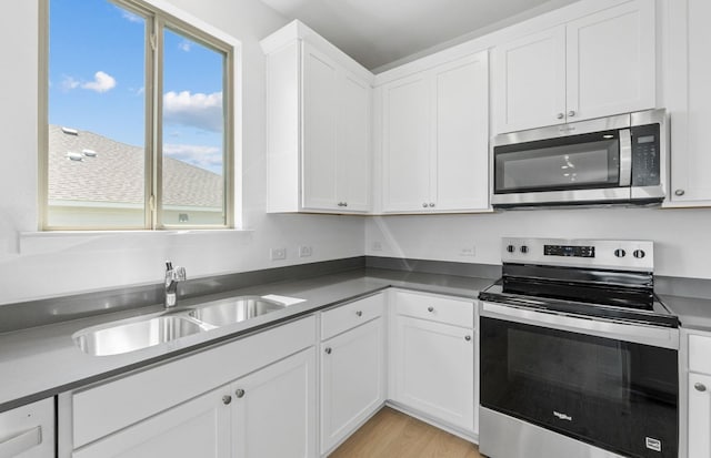 918 Childress Dr, Temple, TX 76501 - kitchen featuring appliances with stainless steel finishes, white cabinetry, light wood-style floors, and dark countertops
