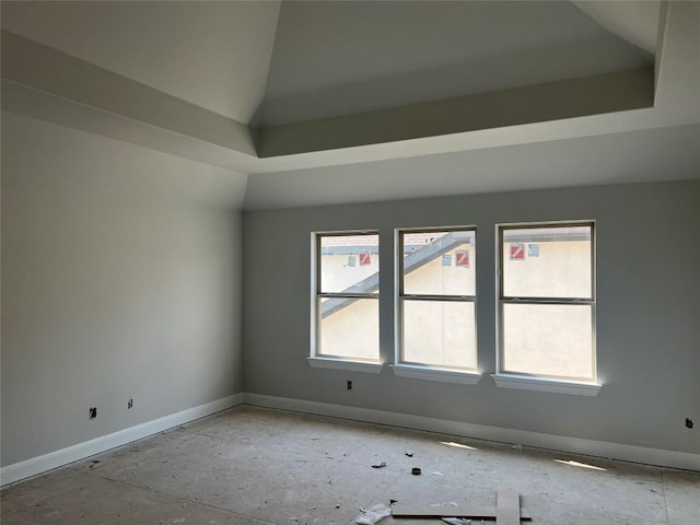 spare room featuring baseboards, lofted ceiling, and a wealth of natural light