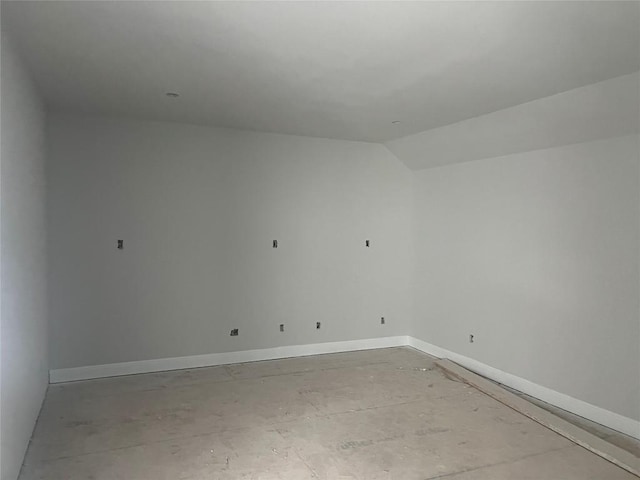 spare room with baseboards and vaulted ceiling