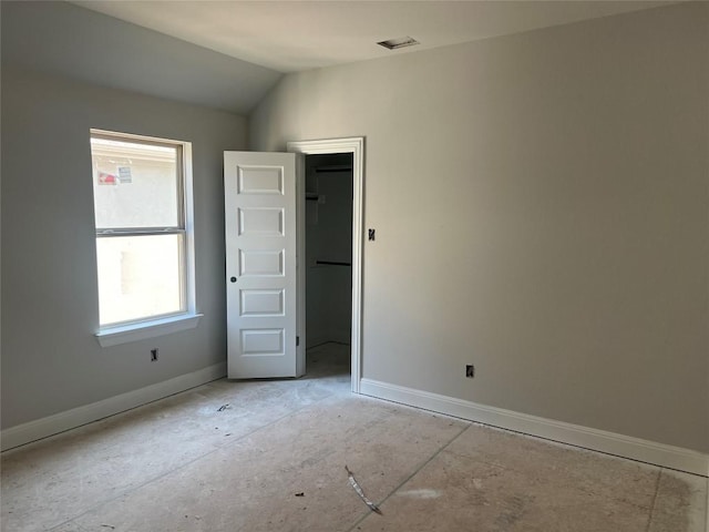 spare room featuring baseboards and lofted ceiling