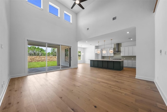 5513 Olimpico Way, Leander, TX 78641 - unfurnished living room with ceiling fan, a towering ceiling, light wood-style flooring, and plenty of natural light