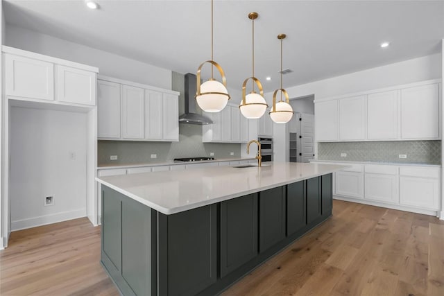 5513 Olimpico Way, Leander, TX 78641 - kitchen with wall chimney range hood, cooktop, tasteful backsplash, white cabinetry, and light wood-style flooring