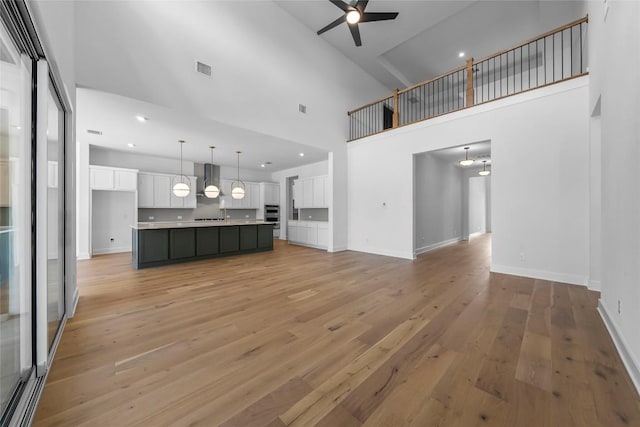 5513 Olimpico Way, Leander, TX 78641 - unfurnished living room featuring a towering ceiling, a ceiling fan, light wood-style floors, and recessed lighting