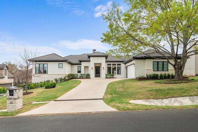 prairie-style home with an attached garage, concrete driveway, stucco siding, and a front lawn