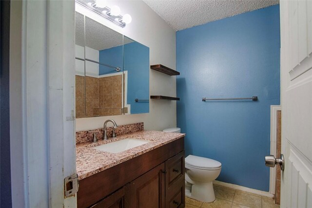 311 August St, Schulenburg, TX 78956 - bathroom featuring walk in shower, toilet, a textured ceiling, vanity, and tile patterned flooring