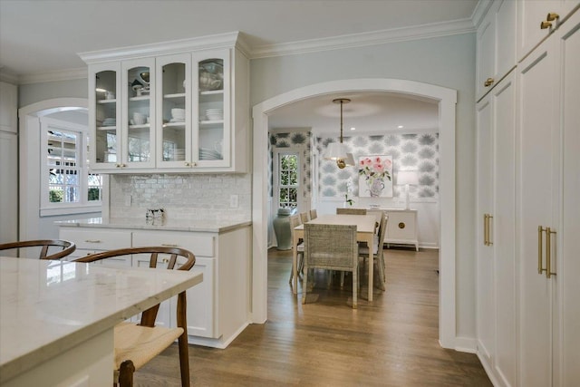 1710 Mccall Rd, Austin, TX 78703 - dining area featuring arched walkways, dark wood-style flooring, and crown molding
