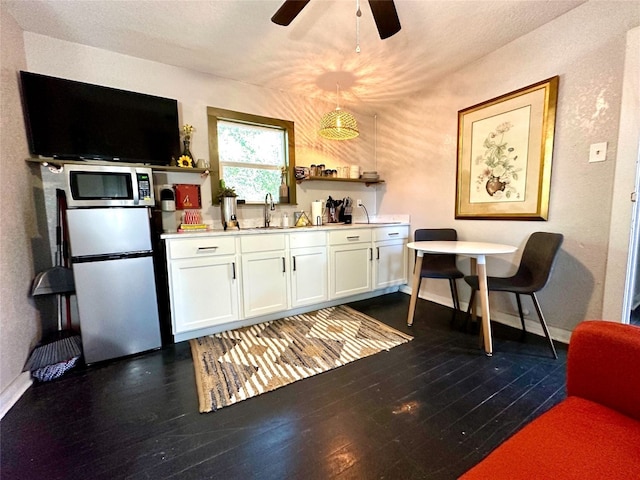 kitchen featuring stainless steel appliances, dark wood-style flooring, white cabinetry, and ceiling fan