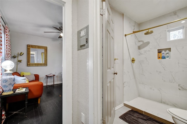 bathroom featuring toilet, a ceiling fan, hardwood / wood-style floors, and a marble finish shower