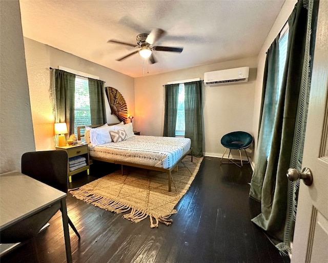 bedroom featuring baseboards, a wall mounted air conditioner, a textured ceiling, ceiling fan, and hardwood / wood-style flooring