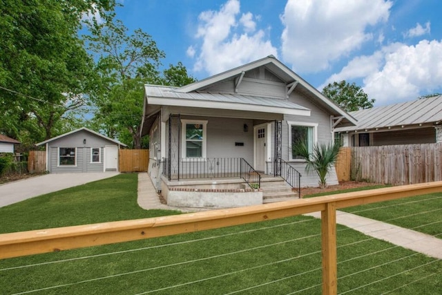 bungalow-style home featuring a front yard, an outbuilding, metal roof, fence, and covered porch