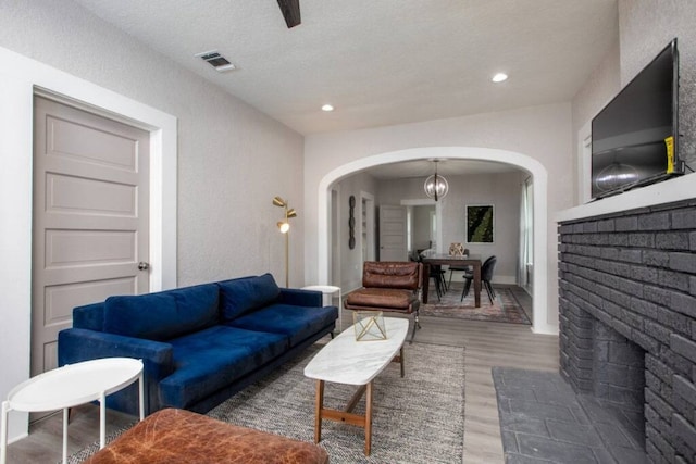 living area with recessed lighting, arched walkways, visible vents, and wood finished floors