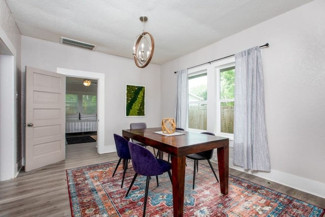 dining area with visible vents, baseboards, a notable chandelier, and wood finished floors