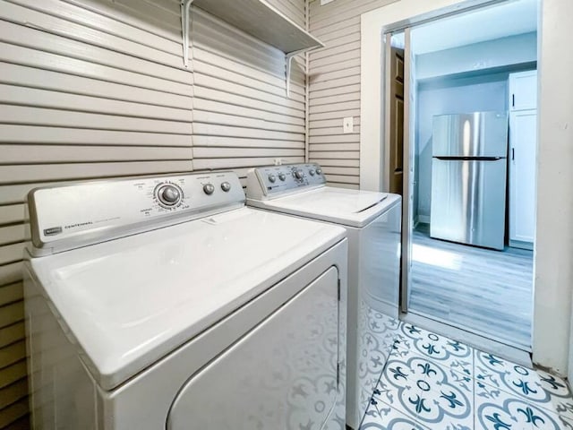 washroom featuring wooden walls, separate washer and dryer, and laundry area
