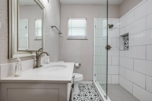 full bath with a tile shower, vanity, tile patterned flooring, toilet, and a textured wall