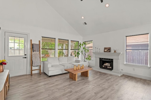 13436 Moscow Trl, Austin, TX 78729 - living area featuring high vaulted ceiling, a fireplace with raised hearth, light wood finished floors, baseboards, and ceiling fan