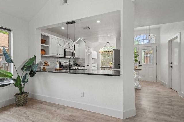 kitchen featuring open shelves, dark countertops, stainless steel microwave, and a healthy amount of sunlight