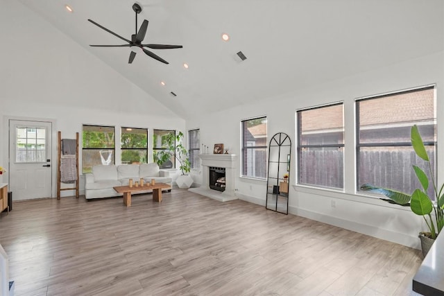 13436 Moscow Trl, Austin, TX 78729 - living room featuring high vaulted ceiling, ceiling fan, a fireplace with raised hearth, light wood finished floors, and recessed lighting