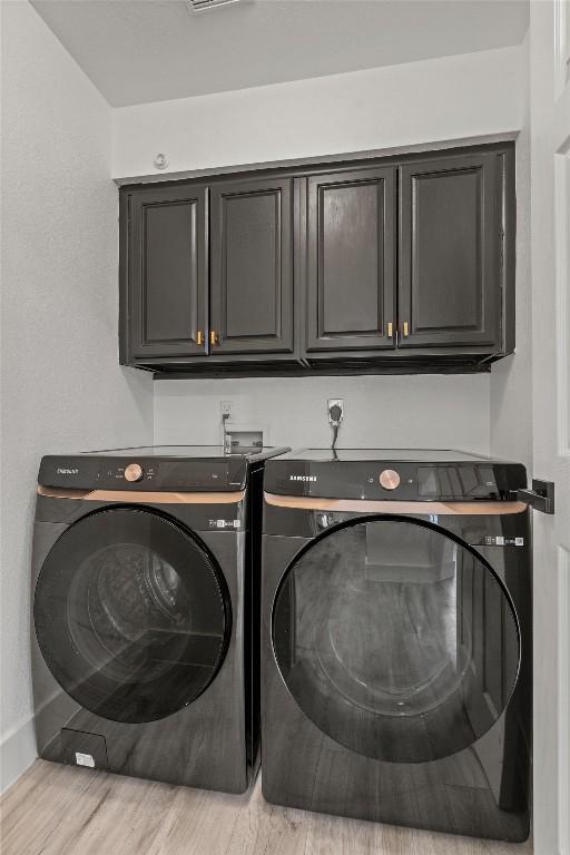 13436 Moscow Trl, Austin, TX 78729 - laundry room with cabinet space, washing machine and dryer, light wood-style flooring, and baseboards