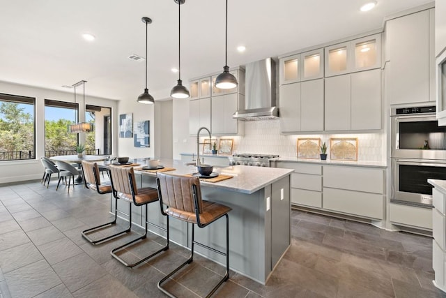 17809 Maritime Point Dr, Jonestown, TX 78645 - kitchen featuring stainless steel double oven, visible vents, a center island with sink, a sink, and wall chimney exhaust hood