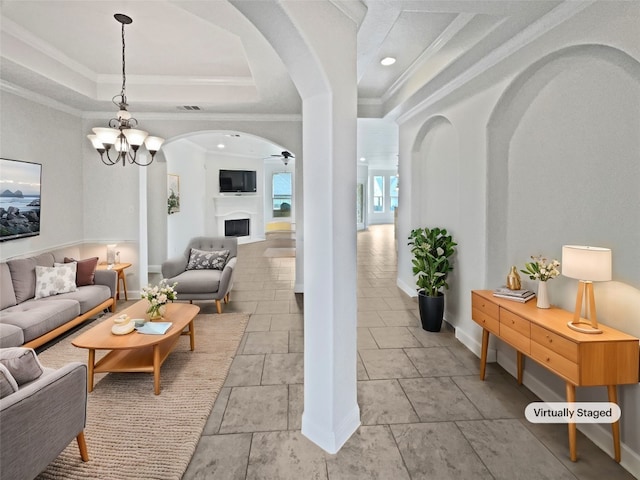 1985 Canyon Sage Path, Round Rock, TX 78665 - living area with arched walkways, crown molding, a tray ceiling, a fireplace, and a ceiling fan