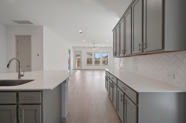 408 Tinto St, Leander, TX 78641 - kitchen with a sink, gray cabinets, a ceiling fan, light wood finished floors, and backsplash