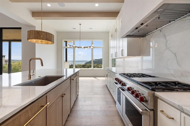 19538 Sandcastle Dr, Spicewood, TX 78669 - kitchen with wall chimney exhaust hood, a sink, high end stainless steel range, backsplash, and light wood-style flooring