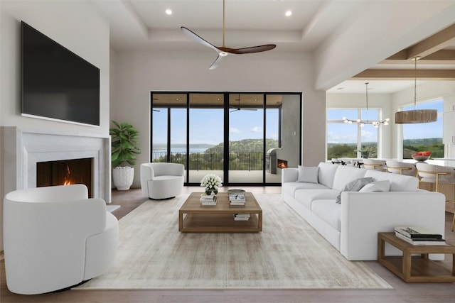 19538 Sandcastle Dr, Spicewood, TX 78669 - living area featuring a raised ceiling, ceiling fan with notable chandelier, a high ceiling, and a warm lit fireplace