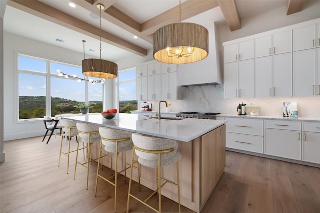19538 Sandcastle Dr, Spicewood, TX 78669 - kitchen with beamed ceiling, light wood-style flooring, a sink, light countertops, and decorative backsplash