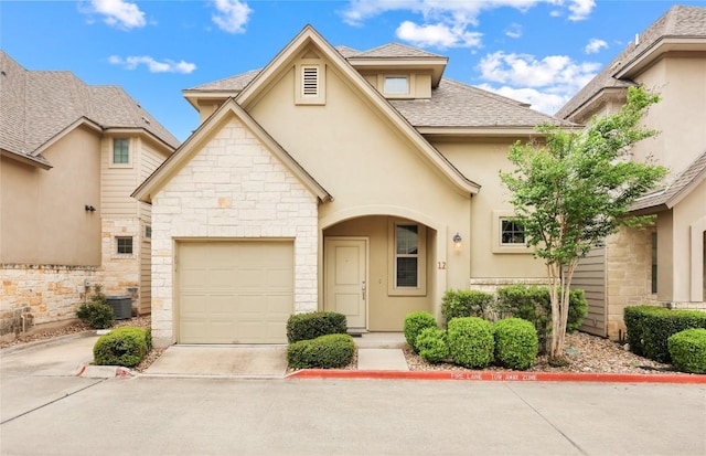 13001 Hymeadow Dr Unit 12, Austin, TX 78729 - view of front of home featuring stucco siding, stone siding, central AC, driveway, and a garage