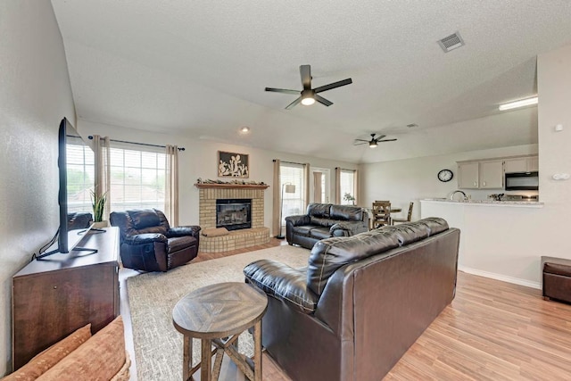 602 Totem Trl, Harker Heights, TX 76548 - living room featuring a ceiling fan, light wood-style flooring, a brick fireplace, and a textured ceiling