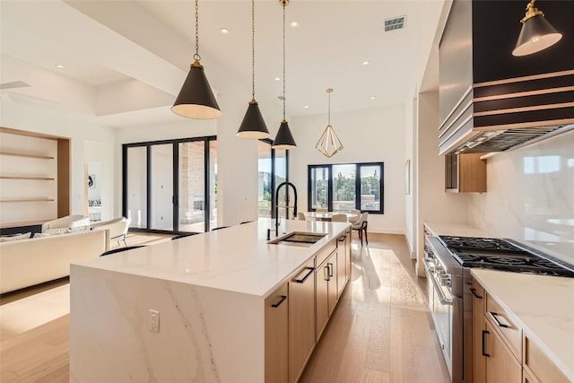 kitchen with high end stove, a sink, light wood-style flooring, open floor plan, and recessed lighting