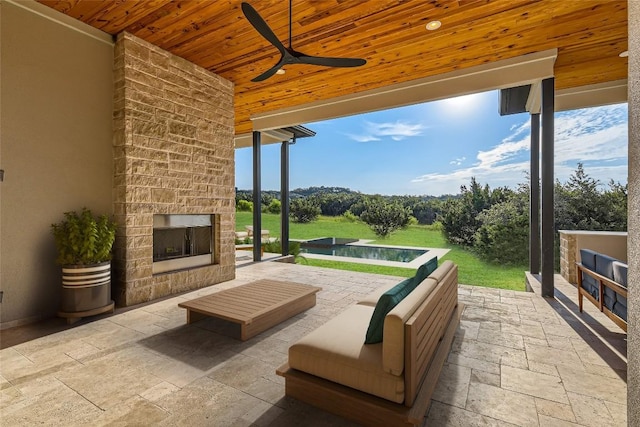 view of patio with ceiling fan and an outdoor living space with a fireplace