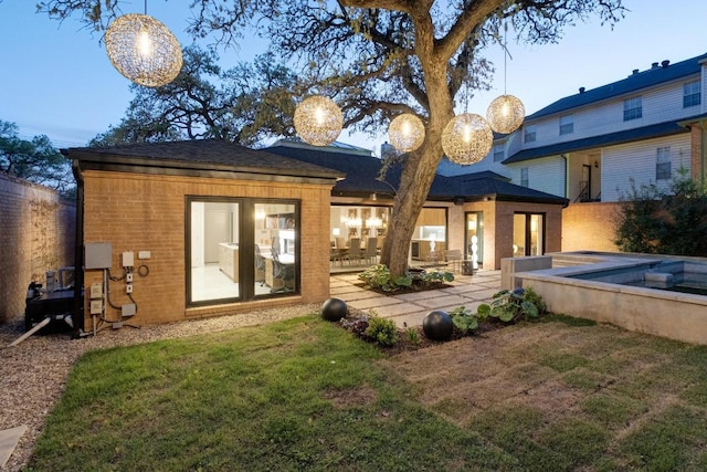 back of house with fence, a patio area, brick siding, and a yard
