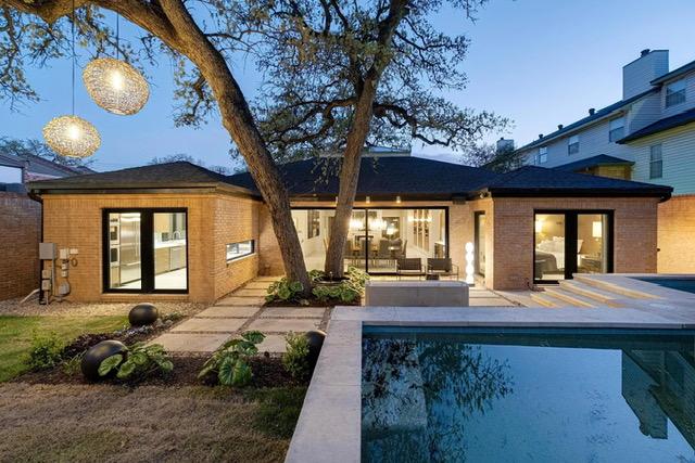 back of property with brick siding, an outdoor pool, and a patio