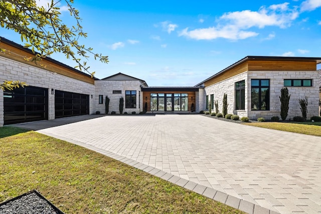 420 Waters Edge Cv, Dripping Springs, TX 78620 - contemporary house featuring stone siding, decorative driveway, a front yard, and a garage