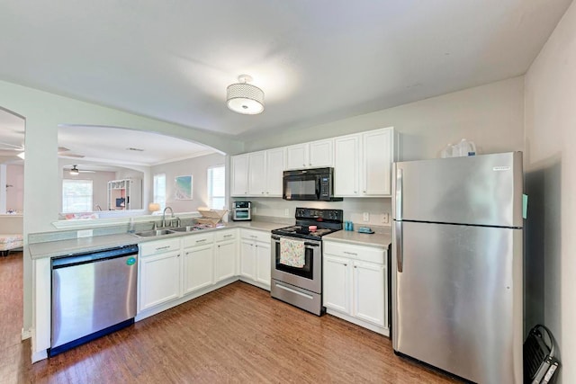 117 Easy St, Hutto, TX 78634 - kitchen featuring appliances with stainless steel finishes, a sink, light wood finished floors, arched walkways, and crown molding