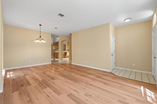 2300 Nevins Cv, Lago Vista, TX 78645 - unfurnished living room featuring arched walkways, light wood-type flooring, and a chandelier