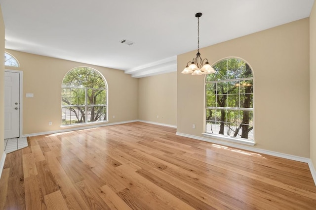 2300 Nevins Cv, Lago Vista, TX 78645 - empty room featuring light wood-style floors, healthy amount of natural light, and a chandelier